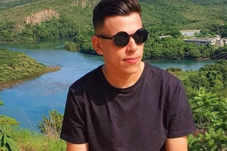 Natan de Souza Martins, 18, de óculos escuros diante de paisagem com rio atrás