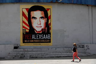 FILE PHOTO: A woman walks by a mural in support of the liberation of Colombian businessman and envoy Alex Saab, who is detained in Cape Verde on charges of laundering money for the government of Venezuelan President Nicolas Maduro, in Caracas
