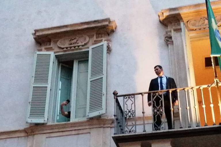 Carlos Bolsonaro foge de eventos oficiais com o pai na Itália e se esconde atrás de janela para filmar apoiadores
