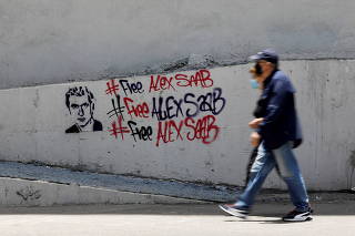 FILE PHOTO: People walk by graffiti in support of the liberation of Colombian businessman and envoy Alex Saab, who is detained in Cape Verde on charges of laundering money for the government of Venezuelan President Nicolas Maduro, in Caracas