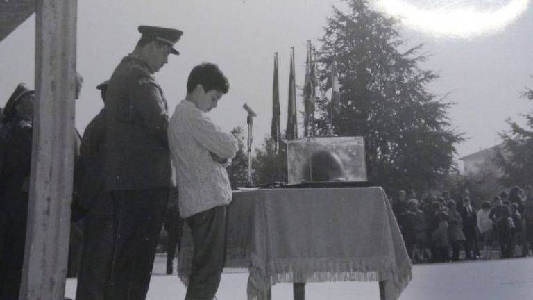 retrato em preto e branco de menino ao lado do pai, soldado fardado, participando de cerimônia
