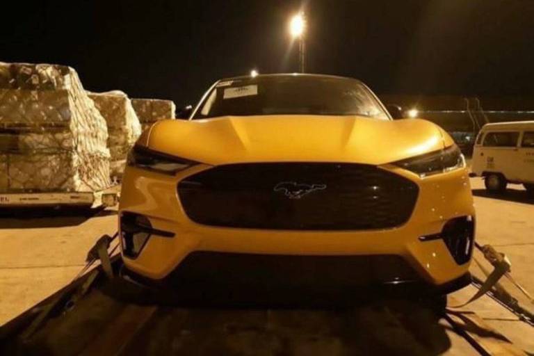Veículo elétrico Mustang Mach-E é visto de frente, estacionado no aeroporto de Viracopos. Ele é amarelo e preto.