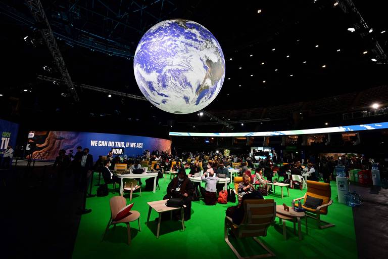 Pessoas sentadas em cadeiras em um espaço decorado com uma imagem gigante do planeta Terra