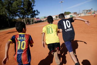Children wearing jerseys with Messi's and Neymar's names play soccer in the neighborhood of Estrutural in Brasilia one day before the start of the Copa America