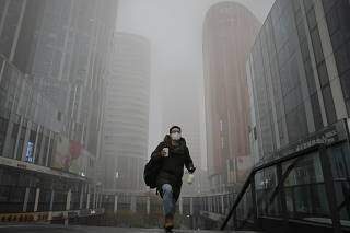 A man walks in the Sanlitun shopping district on a polluted day, in Beijing