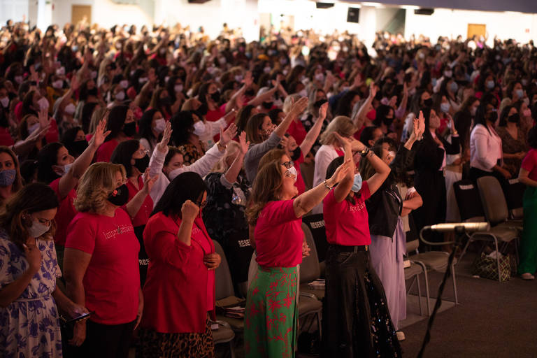 Dezenas de mulheres com as mãos levantadas durante culto
