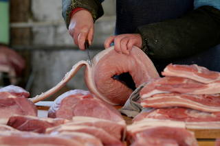 FILE PHOTO: A butcher cuts a piece of pork at a market in Beijing