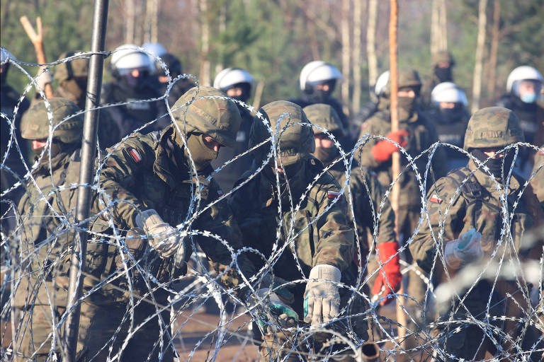 Soldados poloneses trabalham em barreira de arame farpado na fronteira com a Belarus
