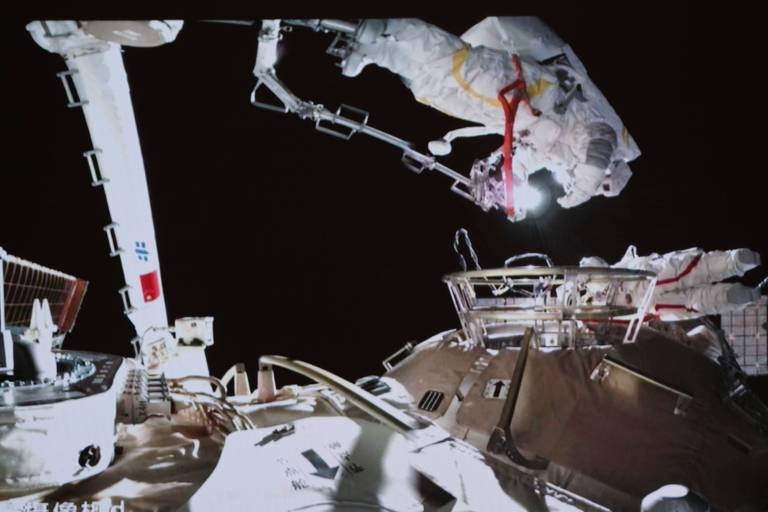 Astronauta caminham do lado de fora do módulo central da estação espacial chinesa