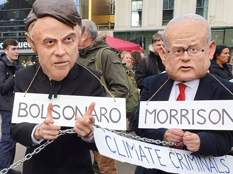 Ativistas com máscaras de líderes mundiais, acorrentados e apresentados como criminosos climáticos