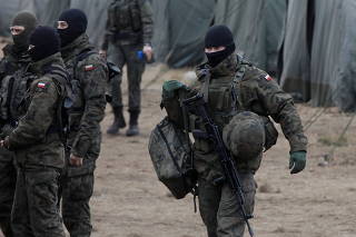 Soldiers from 16th Pomeranian Mechanised Division carry equipment for border duty at their temporary camp during migrant crisis on Belarusian - Polish border near Siemianowka