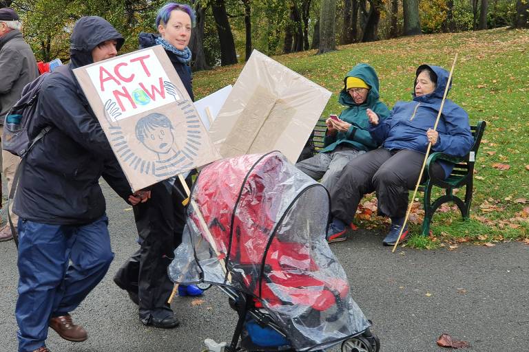 Sob chuva, manifestantes e população protesta contra a crise climática, durante a COP26, em Glasgow