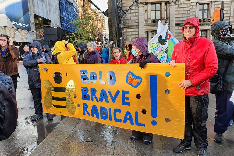 Sob chuva, manifestantes e população protesta contra a crise climática, durante a COP26, em Glasgow