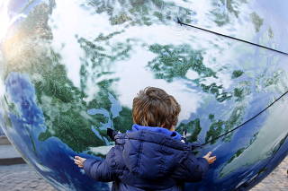 FILE PHOTO: A child embraces a globe shaped balloon during a rally held ahead of the start of the 2015 Paris World Climate Change Conference, known as the COP21 summit, in Rome