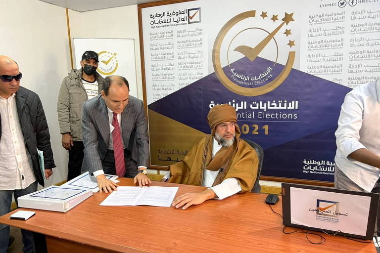 Saif al-Islam (sentado), filho do ex-ditador da Líbia Muamar Kadafi, registra sua candidatura à Presidência do país neste domingo (14)