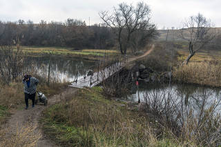 In the town of Hranitne, Ukraine, the access point for shopping for about a hundred people living in the nearby buffer zone is a footbridge crossing the Kalmius River. (Brendan Hoffman/The New York Times)