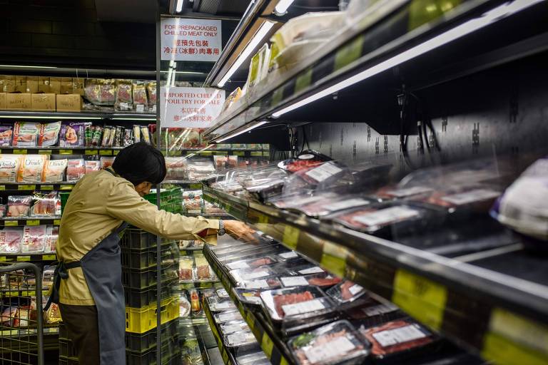 Funcionário retira pacotes de carne de prateleira de supermercado