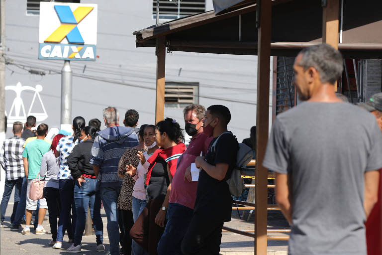 Beneficiários do Auxílio Brasil fazem fila em frente a uma agência da Caixa 
