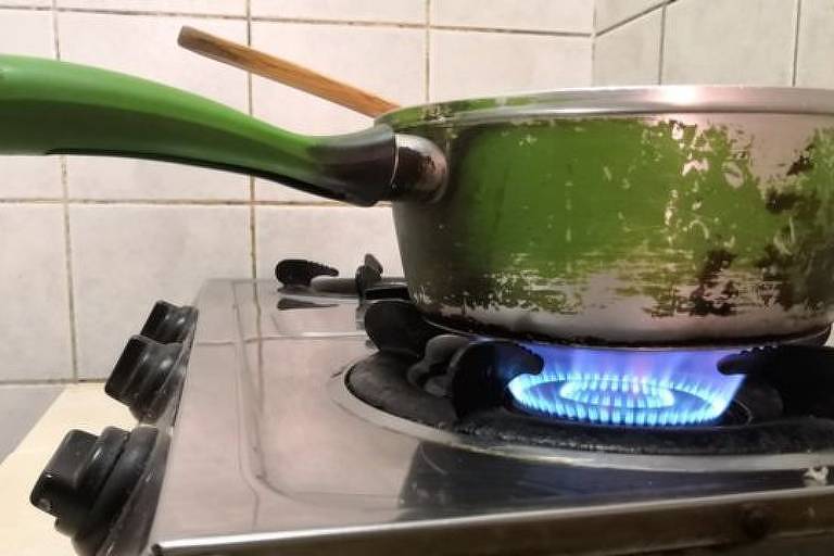 Panela em cima de um fogão com a chama acesa