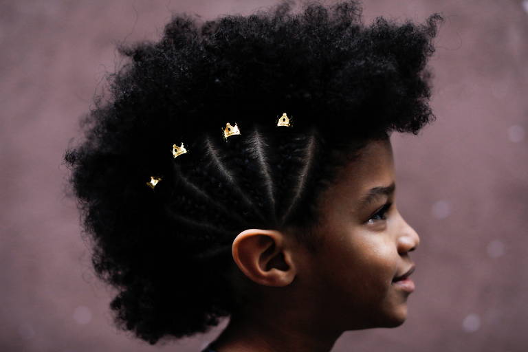Akin, 7, com penteado feito por sua mãe em São Paulo com um padrão antigo da realeza africana
