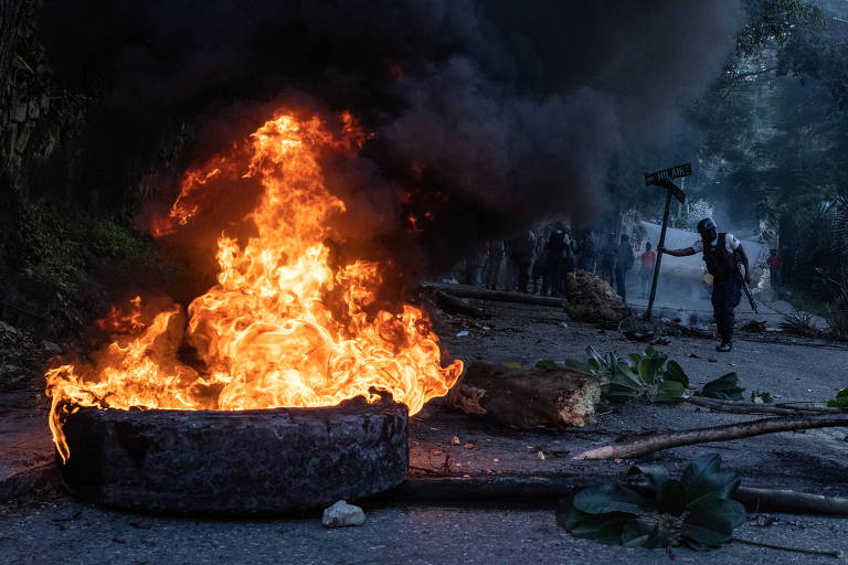 Policial retira pedaços de barricada montada para fechar rua durante protesto contra sequestro em Porto Príncipe, no Haiti