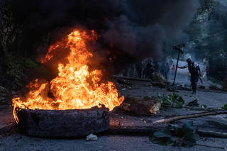 Policeman holds street sign near burning roadblock in Port-au-Prince, Haiti