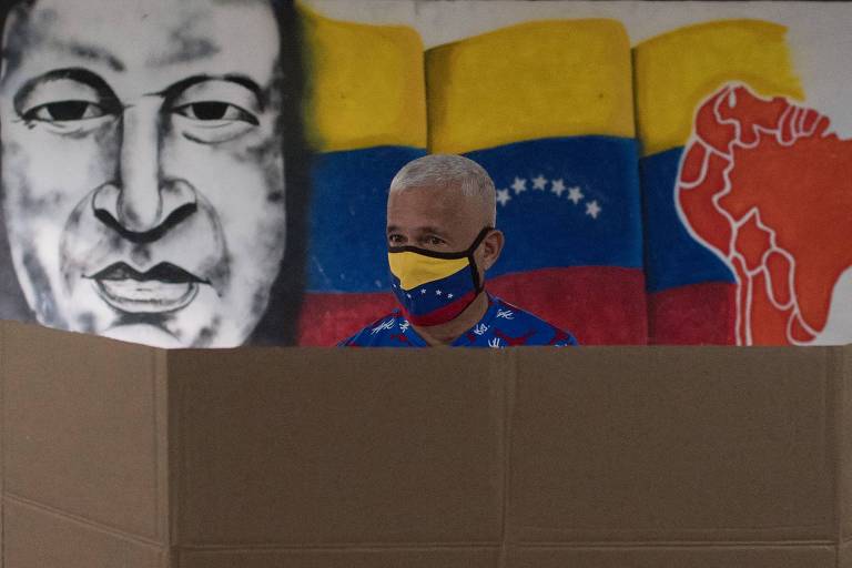 Eleitor de máscara prepara cédula em centro de votação em Caracas, capital da Venezuela