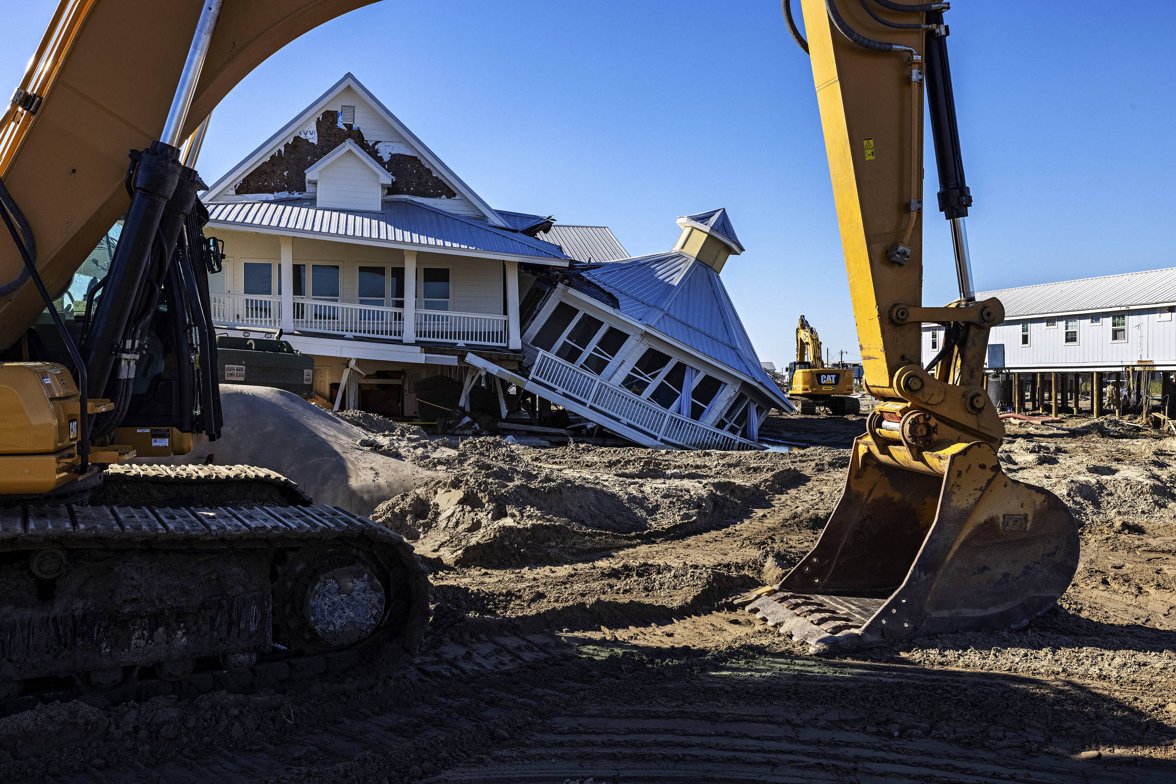Excavators in front of homes destroyed by Hurricane Ida in Grand Isle