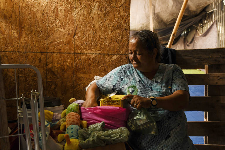 Mulher de meia idade mostra seus mantimentos dentro de um barraco