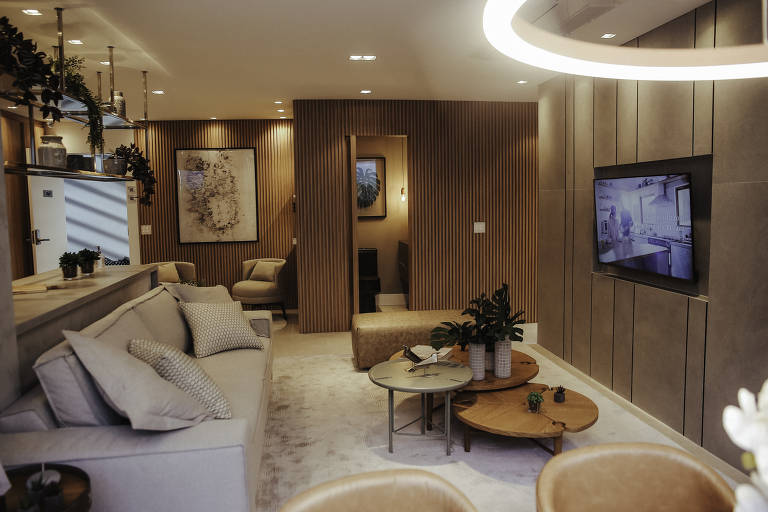 Sala de apartamento com painéis de madeira na parede e sofá cinza