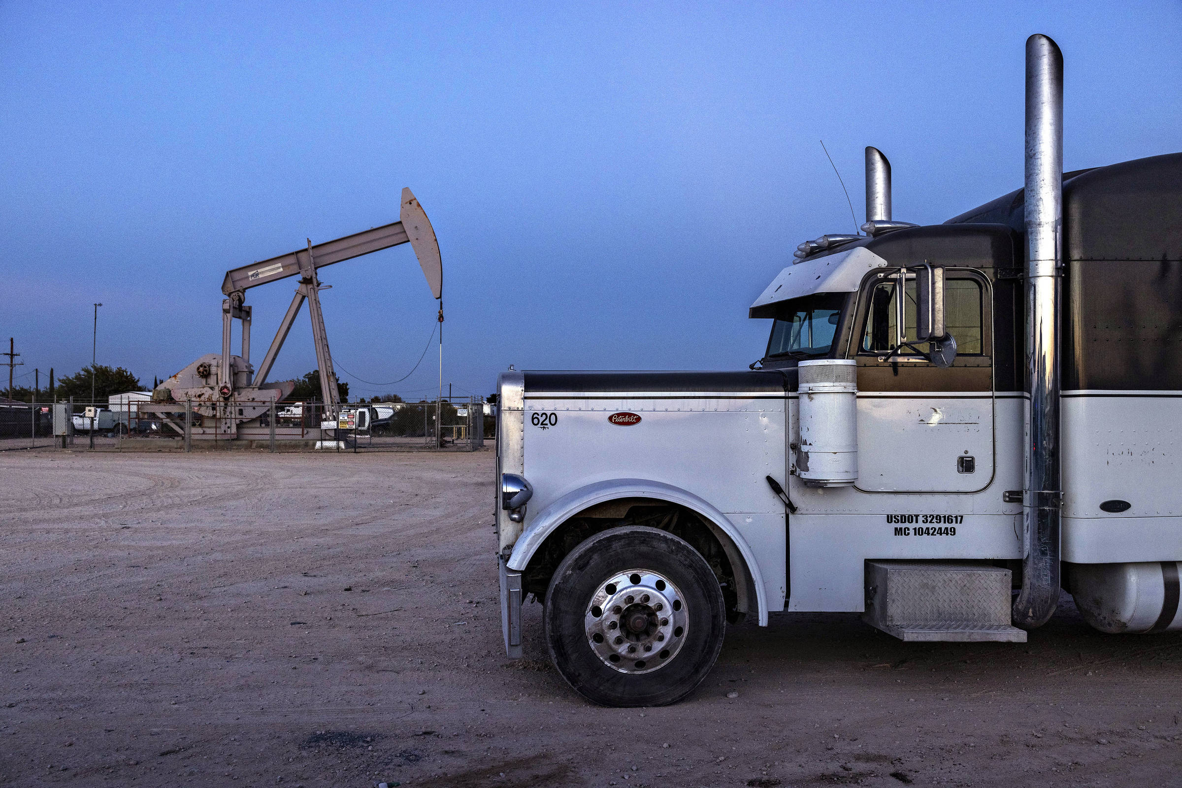 Poço de extração de petróleo ao lado de estacionamento de caminhões próximo à cidade de Odessa, no Texas