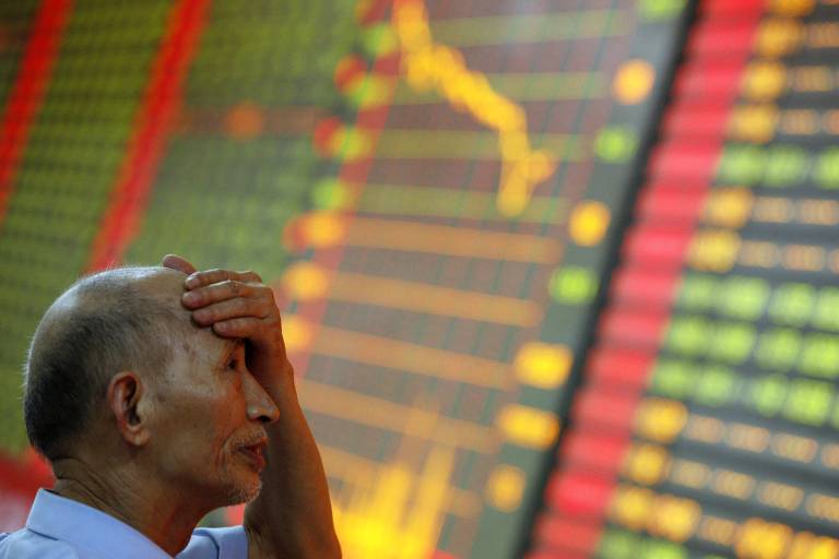 Chinês observa painel com dados sobre ações na Bolsa de Xangai (China)
