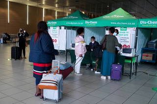 FILE PHOTO: Passengers queue to get a PCR test against COVID-19 before traveling on international flights, at O.R. Tambo International Airport in Johannesburg
