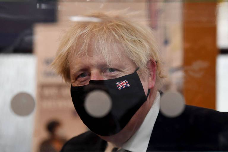 Boris de máscara preta com pequena bandeira da inglaterra, visto atrás de vidro com bolas brancas