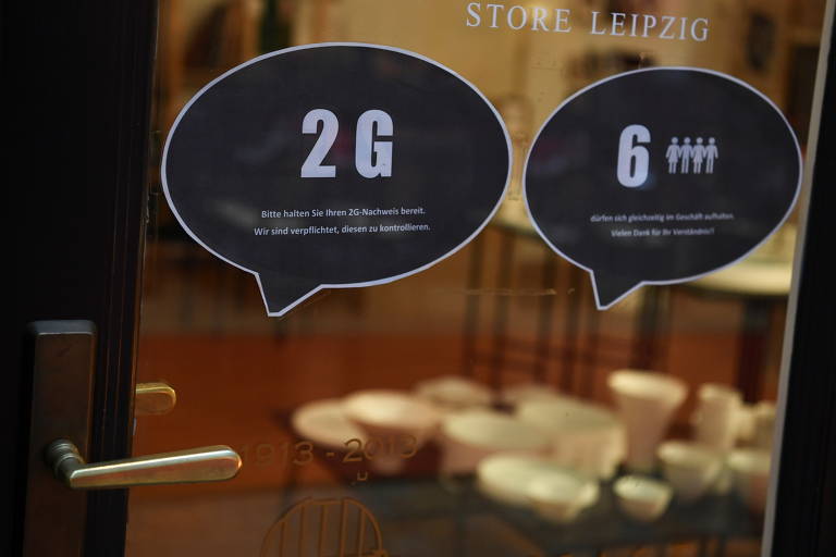 Por que os cientistas se preocuparam?
Porque a variante tem muitas mutações, 50 no total, e mais de 30 na proteína S, usada pelo vírus para entrar nas células e, por isso, base na produção de vacinas; se sua estrutura é muito alterada, há preocupação de que os imunizantes percam eficácia contra ela. Na foto, avisos em janela de loja em Leipzig, na Alemanha, avisa que é preciso estar vacinado para entrar e a lotação é de seis pessoas