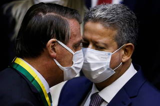 Brazil's President Jair Bolsonaro talks with Brazil's lower house Speaker Arthur Lira during a session of the Chamber of Deputies Medal of Legislative Merit award ceremony in Brasilia