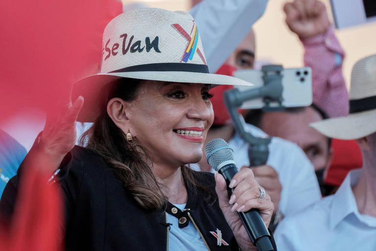Xiomara Castro sorri enquanto fala ao microfone em um palanque