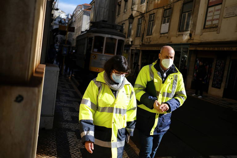 Trabalhadores com máscaras de proteção caminham pelas ruas de Lisboa, capital portuguesa