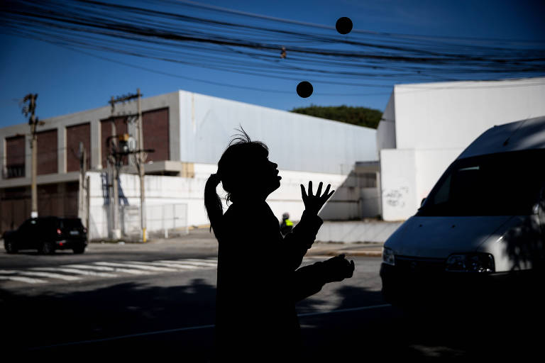 Criança faz malabarismo em frente a semáforo em rua de São Paulo