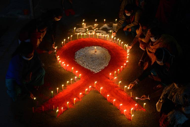 Imagem de uma fita vermelha de prevenção à Aids pintada no chão com velas em volta