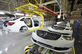 File photo of an employee looking on next to an assembly production line of Buick cars at a General Motors factory in Wuhan