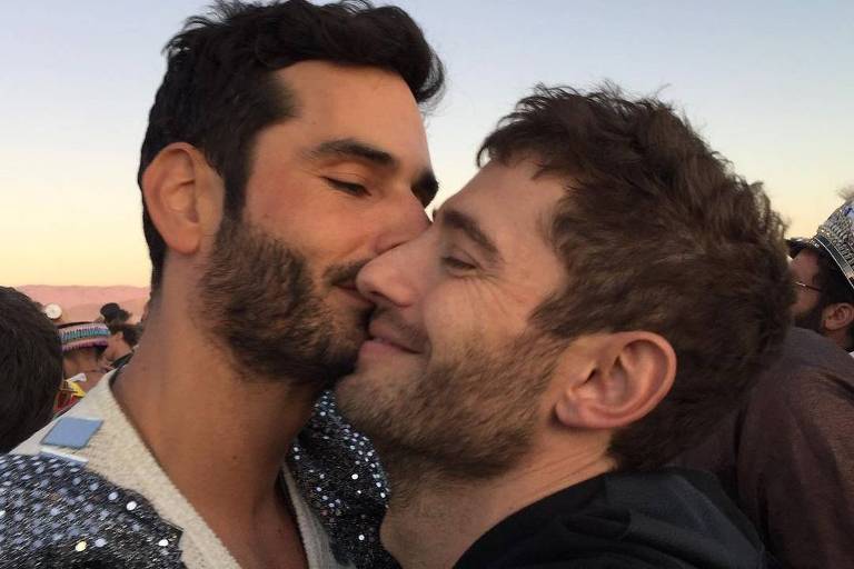 Dois homens se abraçando, enquanto um beija a bochecha do outro