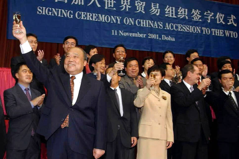 Shi Guangsheng, à esq., então ministro chinês do Comércio e de Cooperação Econômica, celebra a assinatura do acordo de entrada da China à OMC, em Doha