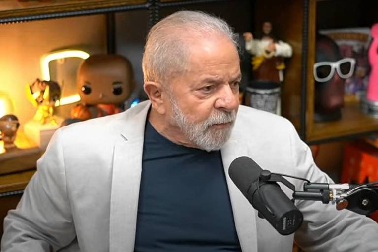 Ex-presidente fala em microfone em estúdio, com objetos expostos atrás