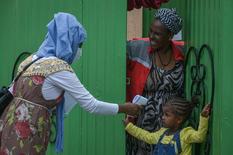 Trabalhadores da saúde medem a temperatura de uma menina durante uma triagem porta a porta para conter a disseminação do coronavírus em Addis Abeba, capital da Etiópia