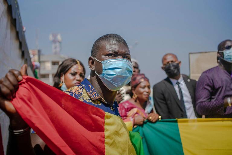 Homem usando máscara segura a bandeira da Guiné-Bissau durante ato em comemoração ao Dia de Independência do país lusófono, que foi colônia de Portugal; a celebração foi adiada por dois meses devido à pandemia de Covid
