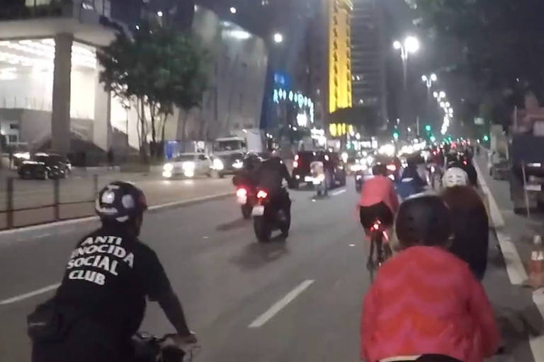 Ciclistas e um motoqueiro vistos de costas na Paulista