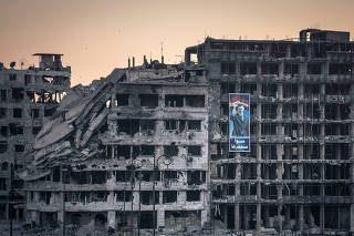 A poster of President Bashar Assad hangs from the ruins of a shopping mall in Homs, Syria, June 15, 2014. (Sergey Ponomarev/The New York Times)