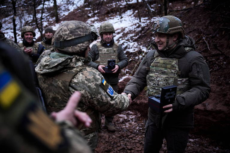 O presidente da Ucrânia, Volodimir Zelenski (dir.), cumprimenta soldado em trincheira na linha de frente do conflito contra separatistas pró-Rússia