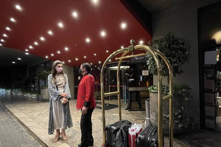 Marina Gryczynski, 26, última hóspede do hotel Maksoud Plaza, conversa com um dos funcionários remanescentes antes de deixar o hotel. Ela está de pé do lado de fora do hotel e conversa com um concierge, que veste vermelho.